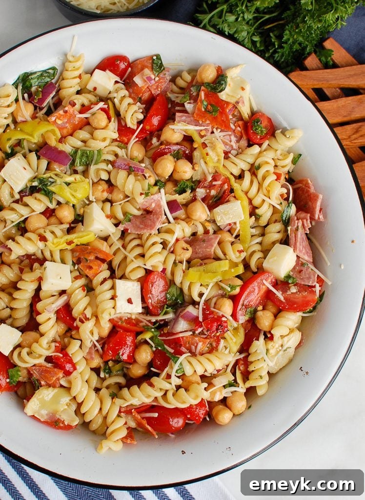 Italian Pasta Salad served in a large wooden bowl with wooden serving utensils, highlighting its readiness for sharing.