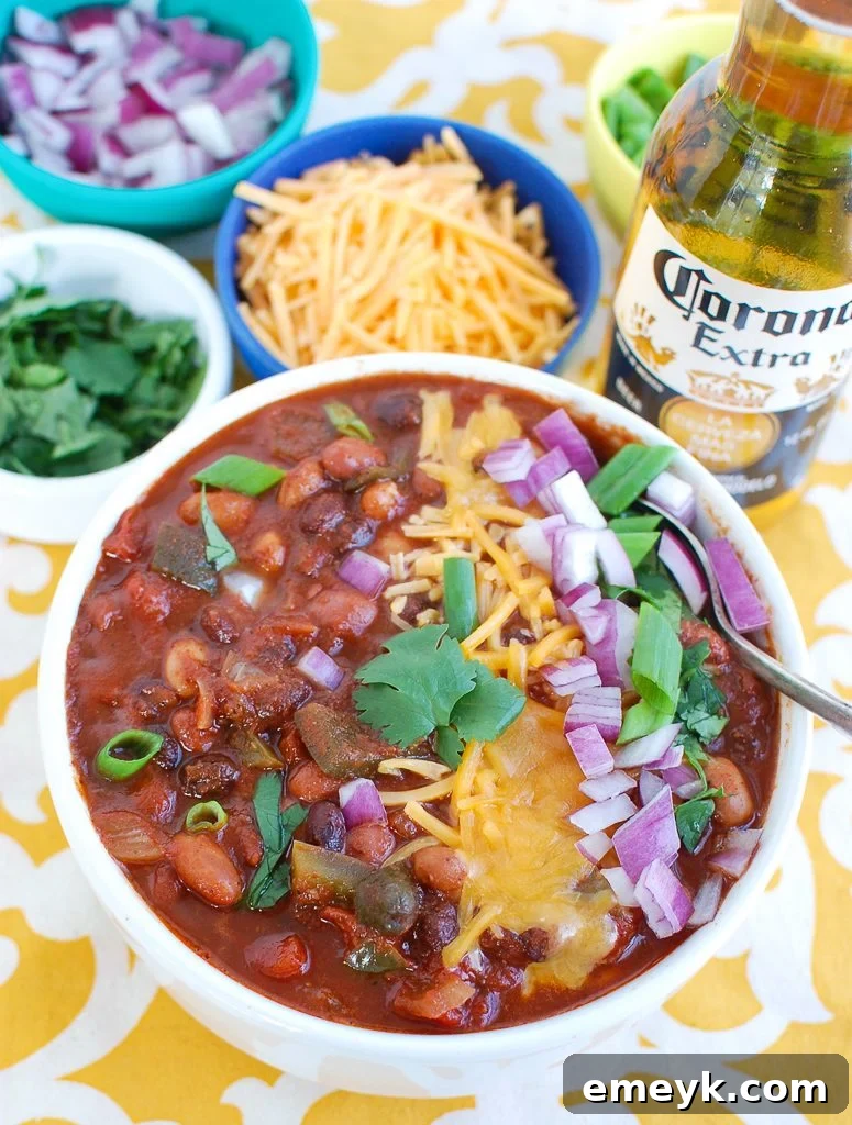Close-up of a rustic white bowl filled with Slow Cooker Vegetarian Chili, highlighting the vibrant beans and diced vegetables