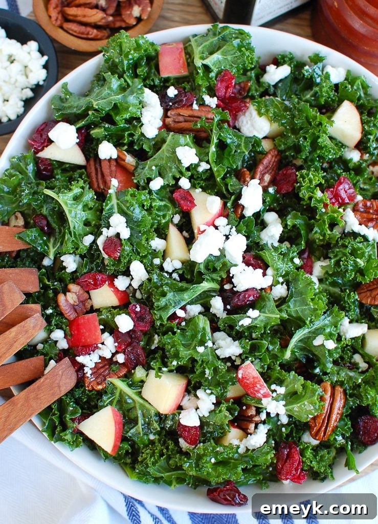 Kale Salad with Cranberries being tossed with elegant wooden tongs, ready to serve