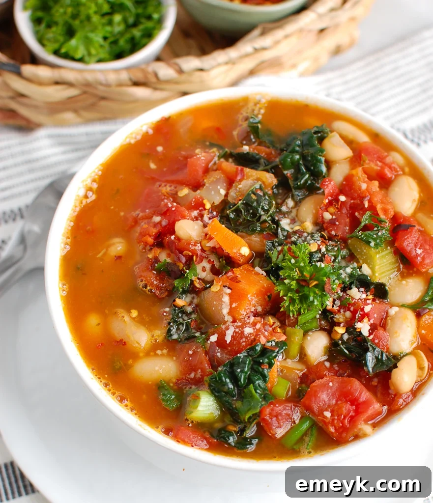 White Bean Soup with Kale in a white bowl, garnished with fresh herbs