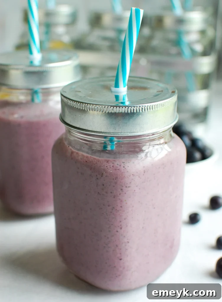 A refreshing Blueberry Kale Smoothie in a glass with a teal straw, ready to be enjoyed.