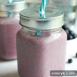 Full glass of Blueberry Kale Smoothie, topped with a few fresh blueberries.