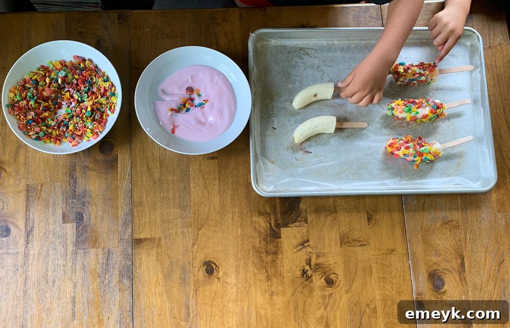 Prepared Banana Crunch Popsicles arranged on a wax paper-lined cookie sheet before freezing