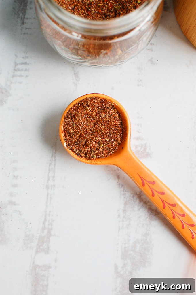 Close-up of various taco seasoning spices on a spoon, showcasing their rich colors.