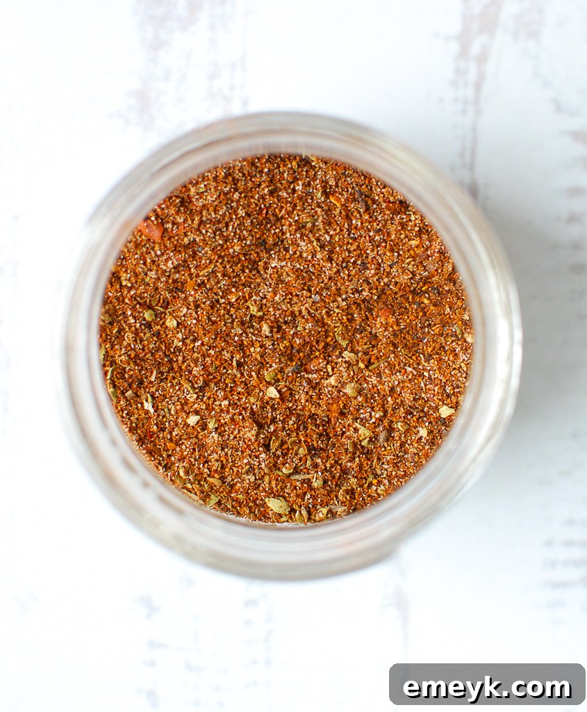 An aerial view of assorted taco seasoning spices artfully arranged around a jar.