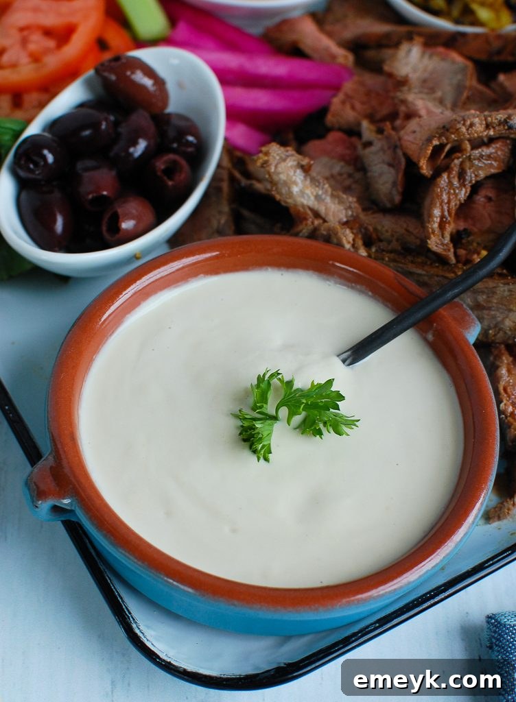 Creamy Tahini Sauce served in a teal bowl, garnished with parsley, ready for dipping or drizzling over Mediterranean dishes.
