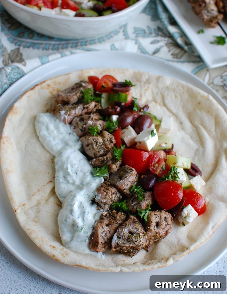 Pork Souvlaki with Tzatziki on a white pita bread, drizzled with tzatziki