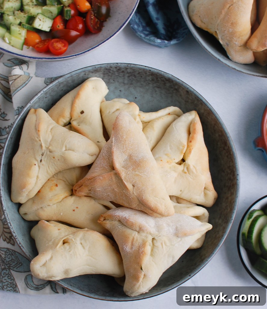 Quick Lebanese Spinach Hand Pies 3 Unbaked spinach and feta fatayer dough triangles arranged in a bowl, ready for baking.