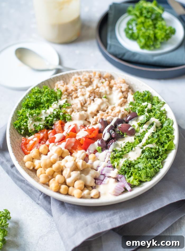 Hearty Mediterranean Farro Salad with lemon tahini sauce, featuring whole grains, fresh vegetables, and herbs in a bowl.