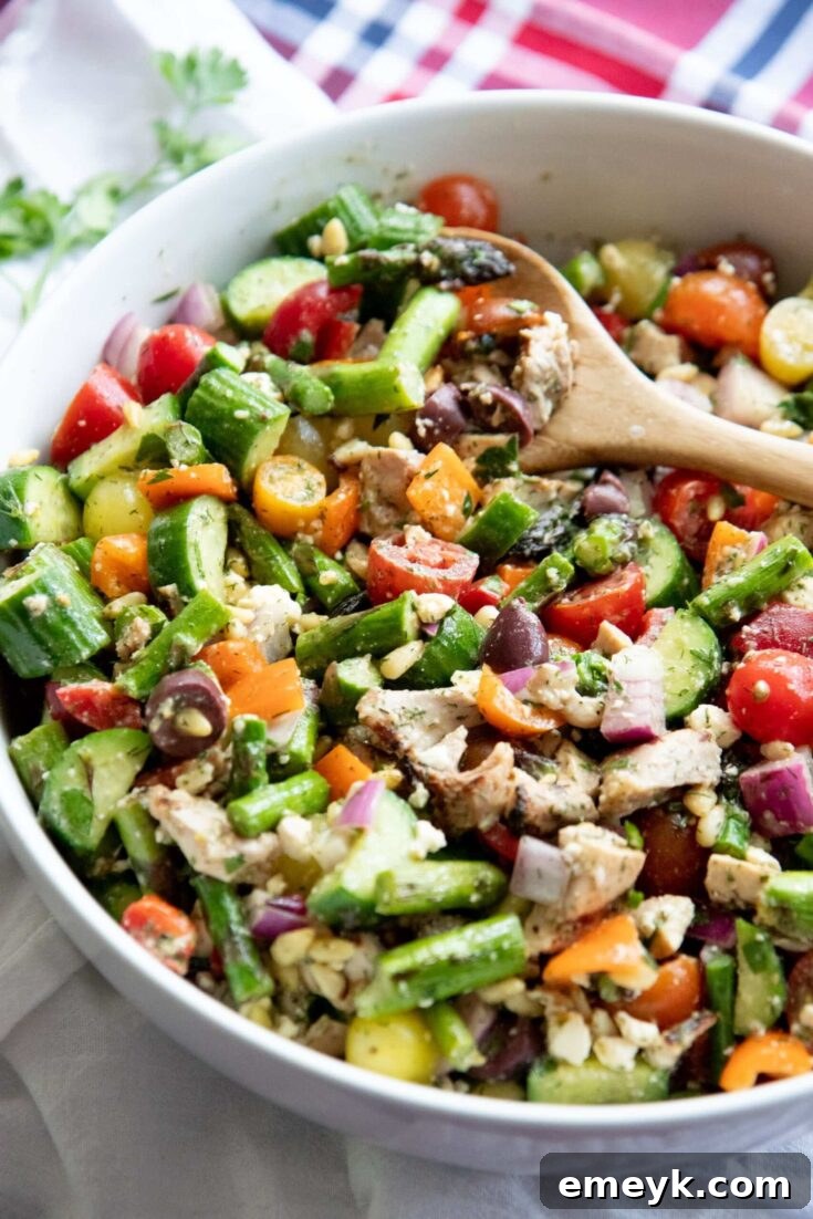 Grilled Chicken and Asparagus Chopped Greek Salad with crisp lettuce, olives, feta, tomatoes, and tender chicken, in a bowl.