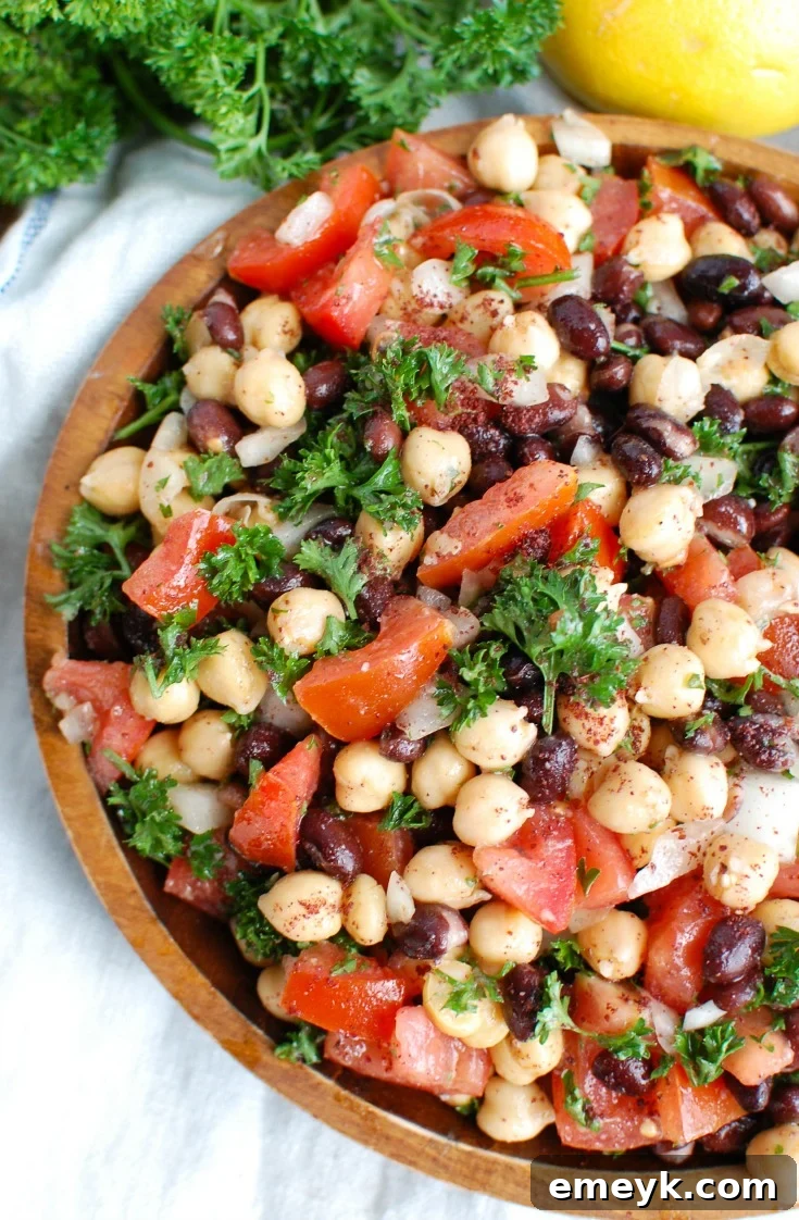 Fresh Balela Salad with chickpeas, black beans, diced tomatoes, cucumbers, and parsley in a light vinaigrette.