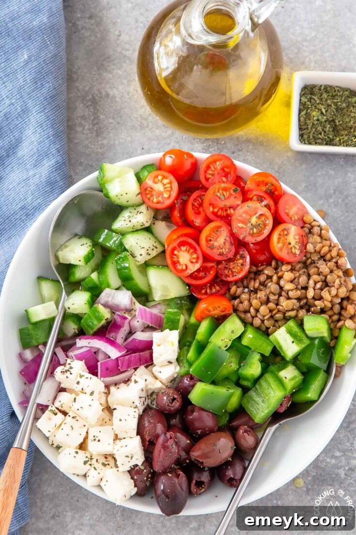 Wholesome Lentil Greek Salad brimming with cooked lentils, cucumbers, tomatoes, feta cheese, and olives, in a vibrant bowl.