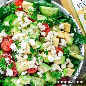 Hearty and healthy Greek Kale Salad with chopped kale, chickpeas, olives, feta, and a bright lemon-herb dressing in a serving bowl.