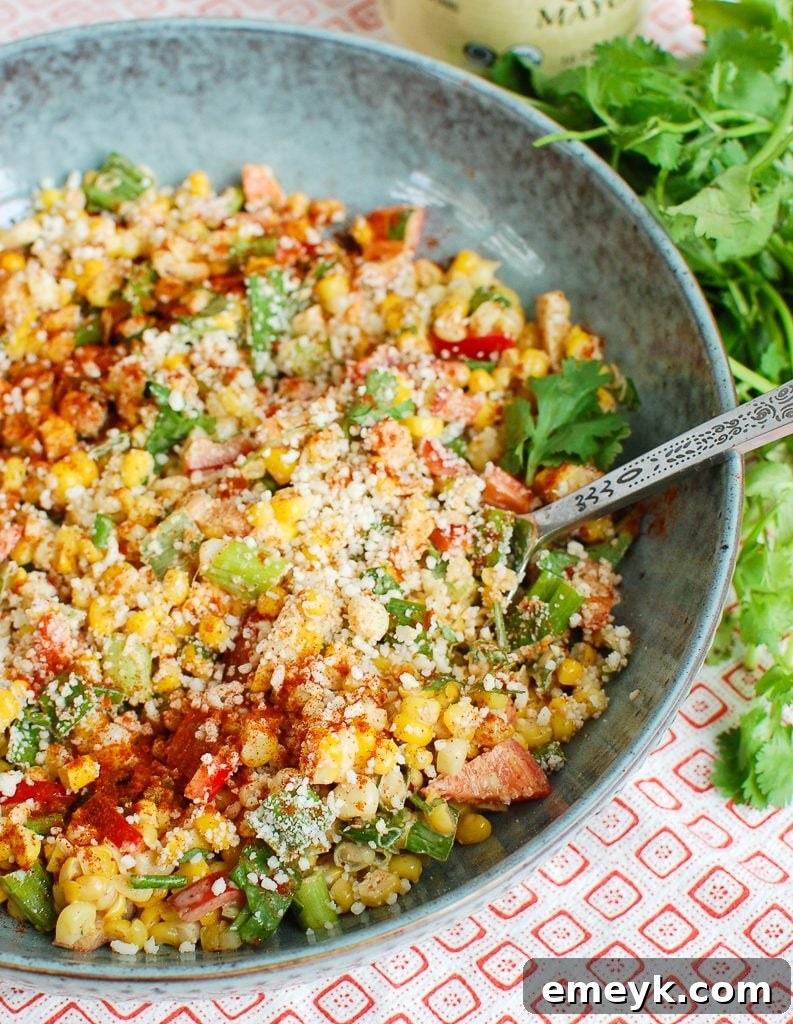 Mexican Corn Salad in teal bowl, garnished with cilantro and lime