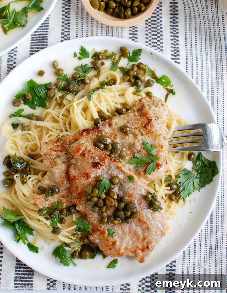 Veal Piccata garnished with fresh parsley on a white plate, ready to be served.
