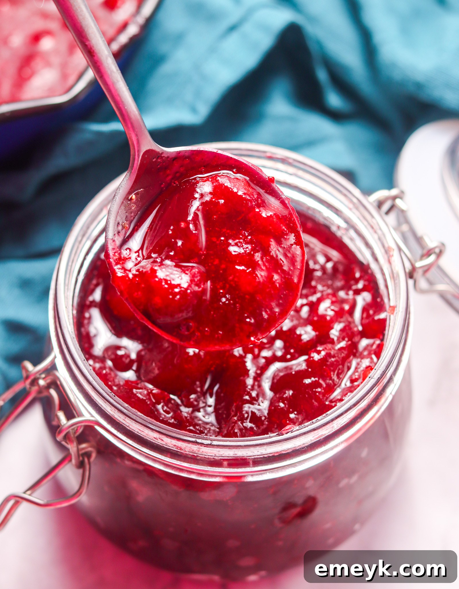 Homemade Cranberry Sauce in a mason jar with a spoon, highlighting its rustic charm.