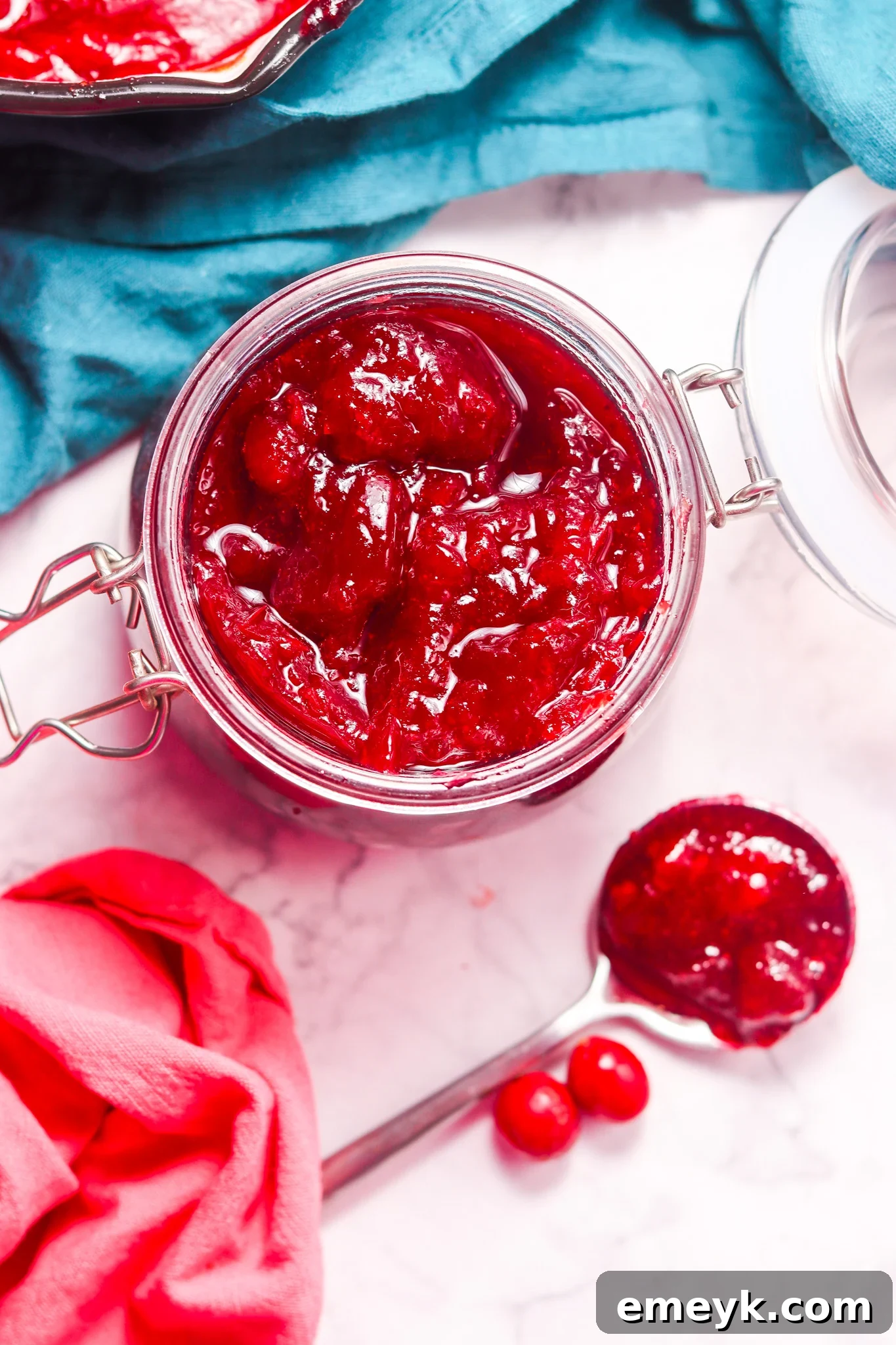 Homemade Cranberry Sauce in a serving bowl with a spoon, garnished with fresh cranberries.