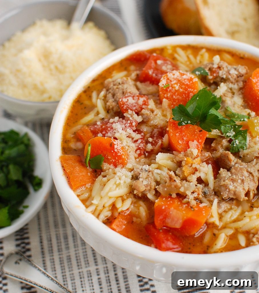 A steaming bowl of hearty Italian Sausage Soup, garnished with fresh herbs.