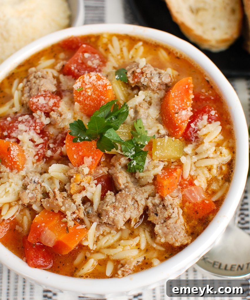 Close-up of Italian Sausage Soup with grated Parmesan cheese melting on top.