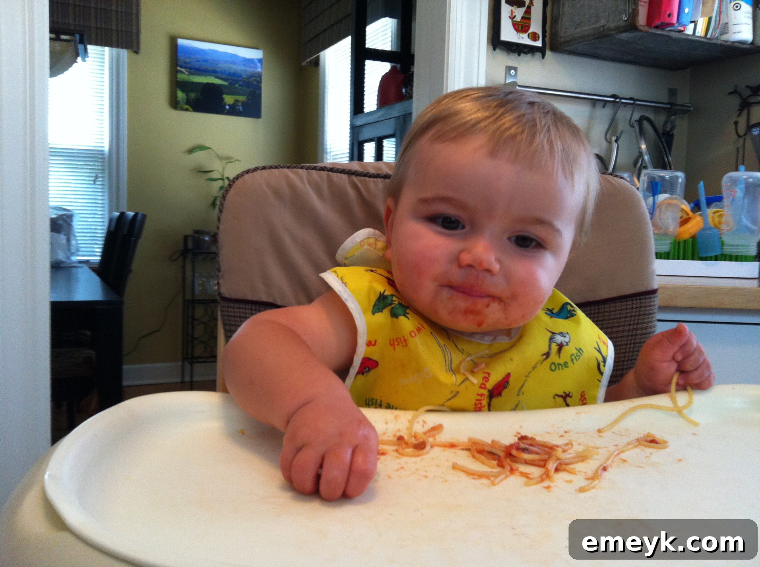 One-year-old baby happily eating spaghetti for the first time