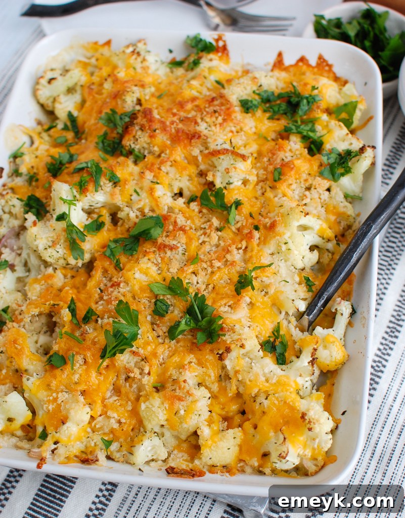 A serving spoon lifting a scoop of creamy Cauliflower Gratin from the baking dish, showing its luscious texture.