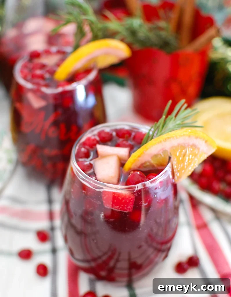 Close-up of Christmas Sangria with an orange slice and cranberries, highlighting its vibrant holiday colors