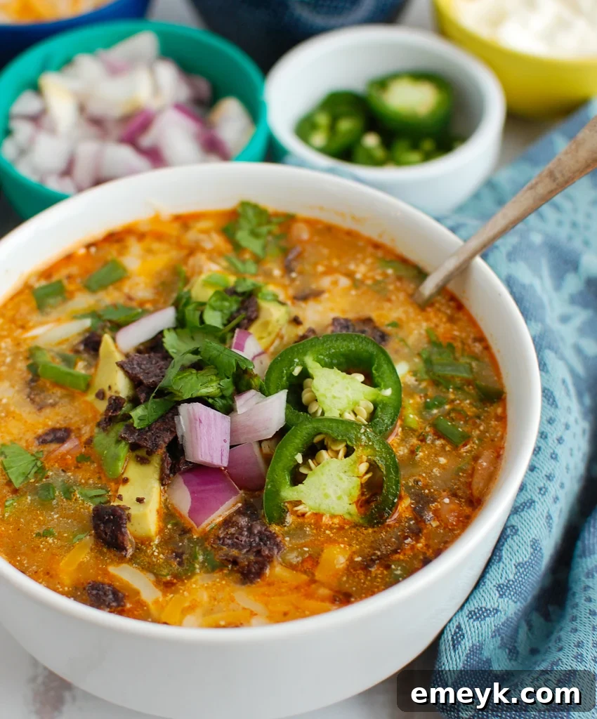 A steaming bowl of Instant Pot White Chicken Chili, garnished with fresh cilantro and a dollop of sour cream, in a rustic white bowl.