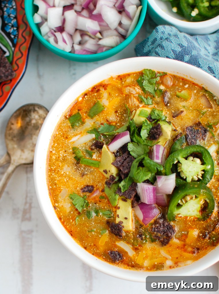 A close-up of Instant Pot White Chicken Chili in a bowl, with a spoon ready to serve, showcasing its creamy texture and shredded chicken.