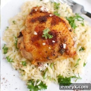 Mediterranean Chicken on a white plate with parsley and a side of orzo.