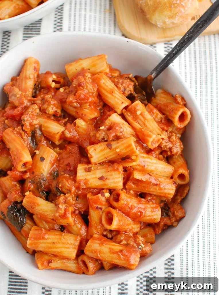 Creamy Italian Sausage Pasta served in a white bowl, garnished with fresh basil.