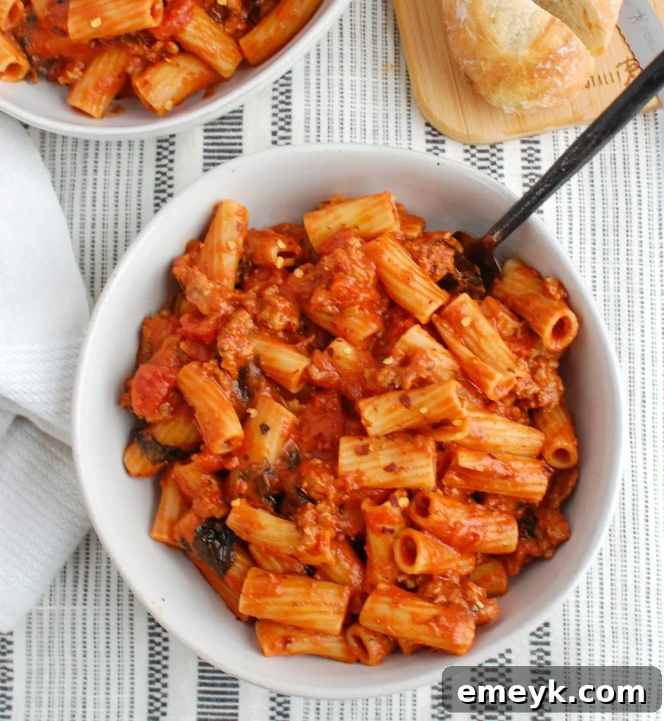 A close-up of Italian Sausage Pasta with a spoon, showing the creamy texture and fresh basil.