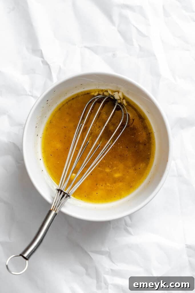 Ingredients for salad dressing in a bowl with a whisk