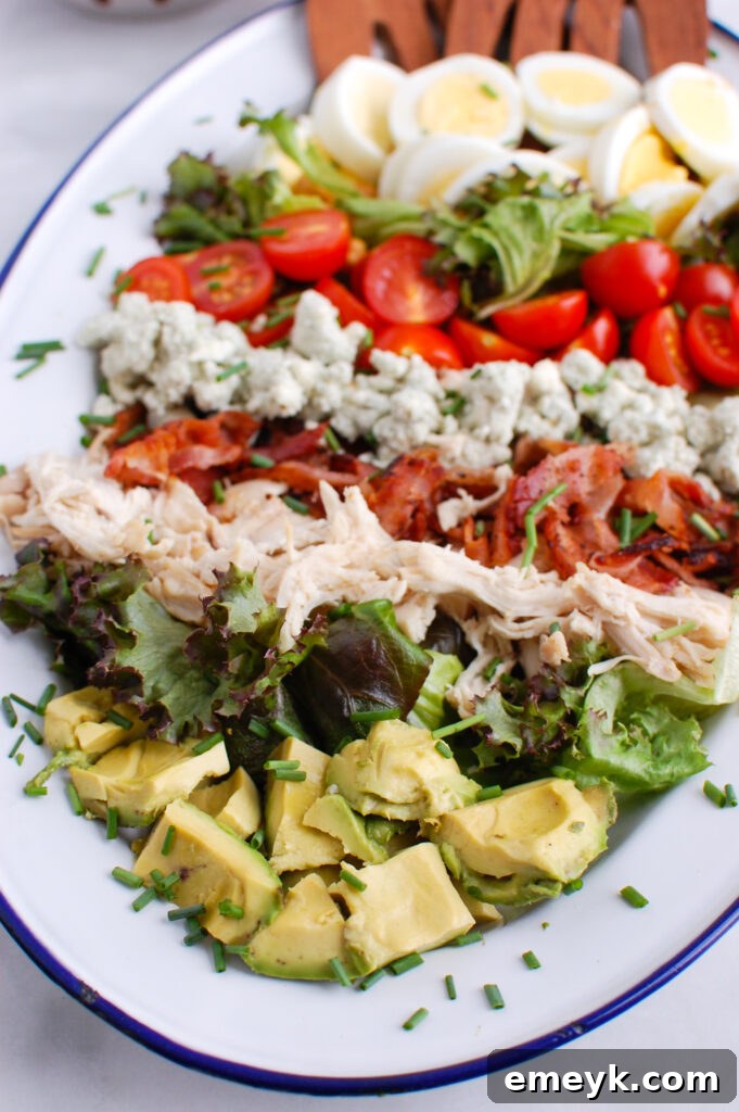 Beautifully arranged Cobb Salad on a large platter, showcasing its vibrant layers of greens, tomatoes, avocado, chicken, bacon, eggs, and blue cheese