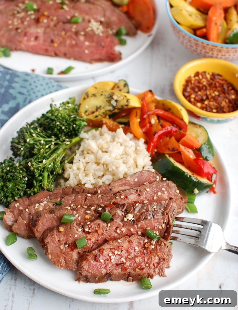 Asian Marinated Flank Steak on white plate with rice and vegetables