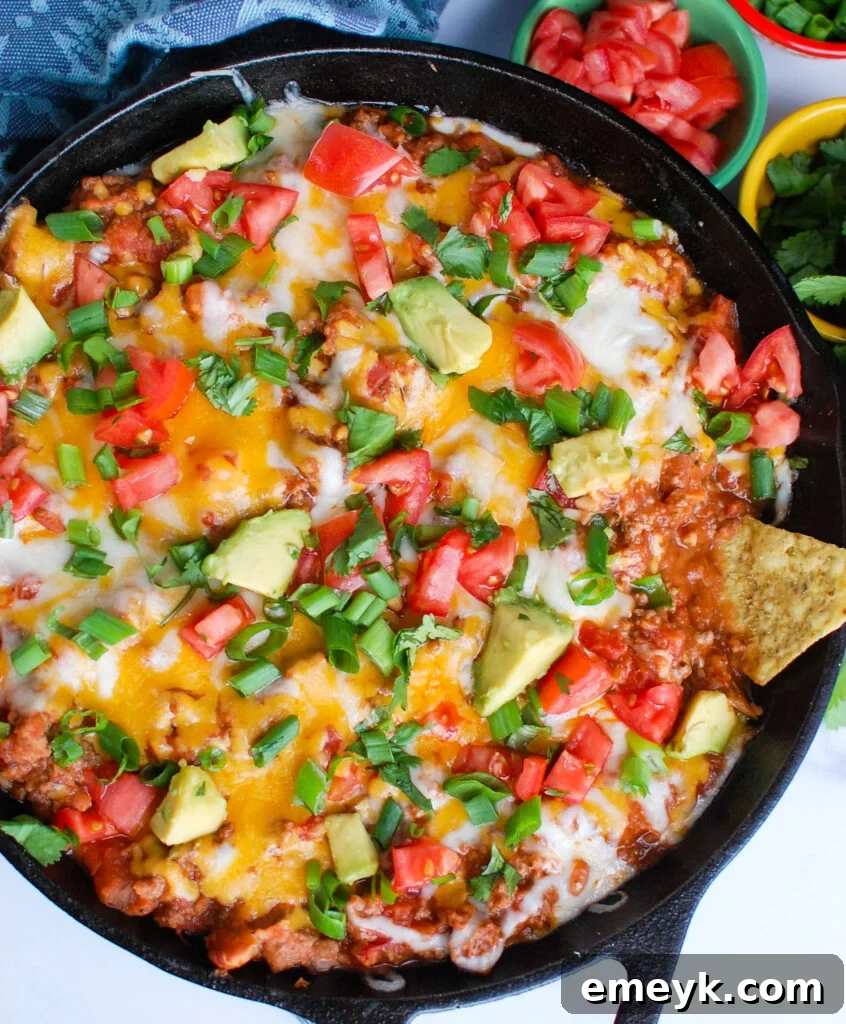Delicious Beef Taco Dip served warm in a skillet with tortilla chips for dipping.