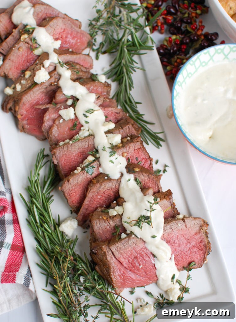 Plated Beef Tenderloin Steaks with Creamy Blue Cheese Sauce, garnished and ready for serving on a white platter.