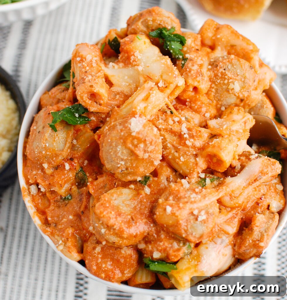 A serving of Italian Sausage Pasta Bake in a white bowl, garnished with fresh herbs