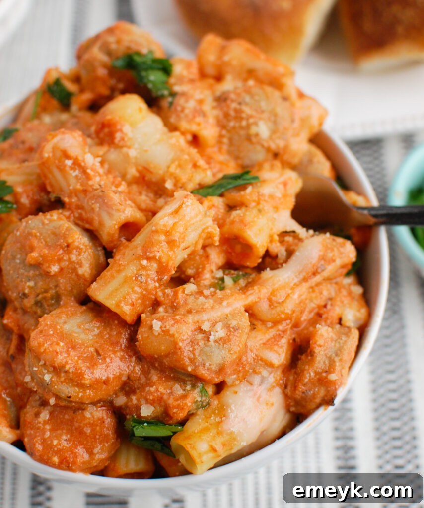 A fork taking a scoop of Italian Sausage Pasta Bake from a white bowl