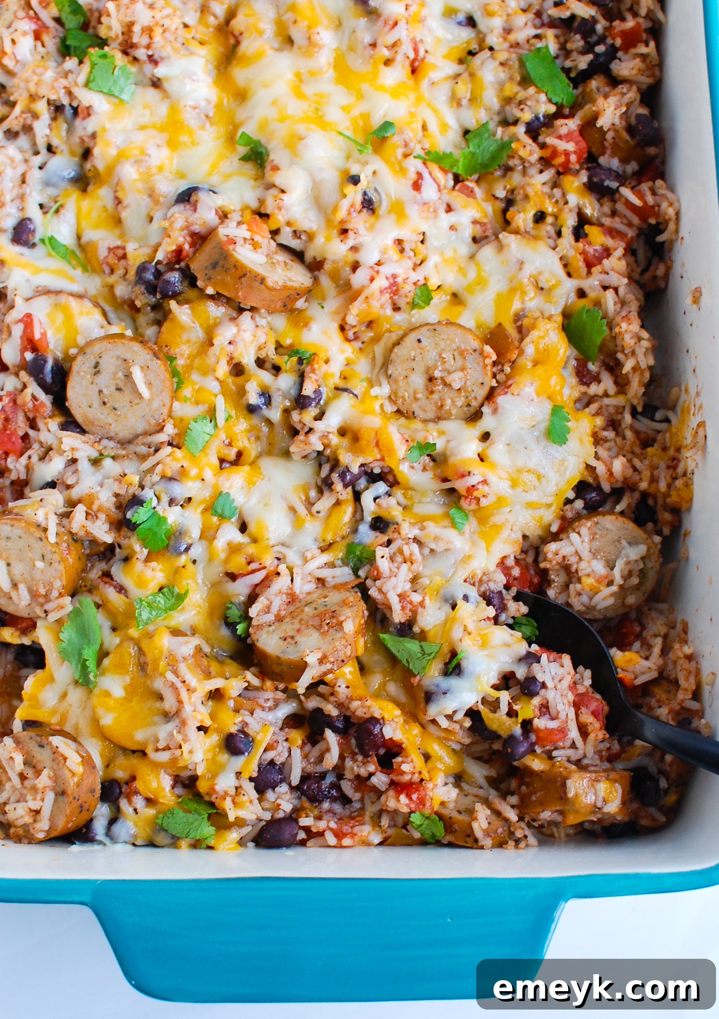 A large baking dish filled with a rich and cheesy sausage and bean casserole, straight from the oven.