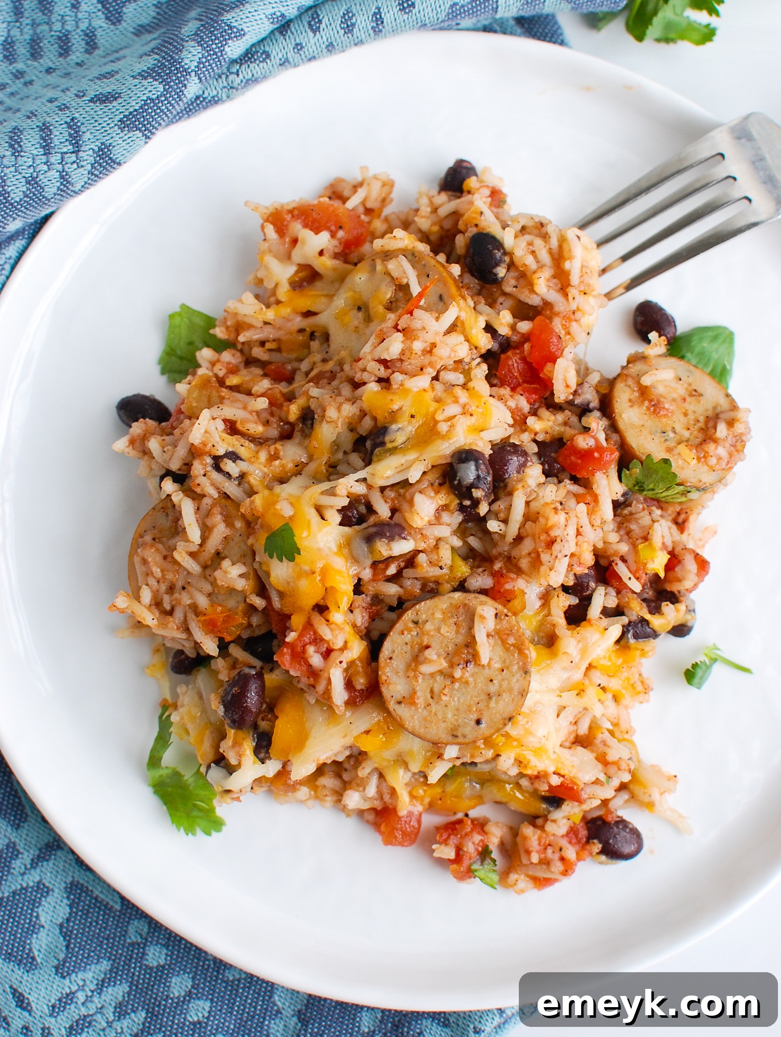 A single serving of sausage and bean casserole beautifully presented on a white plate, ready to eat.