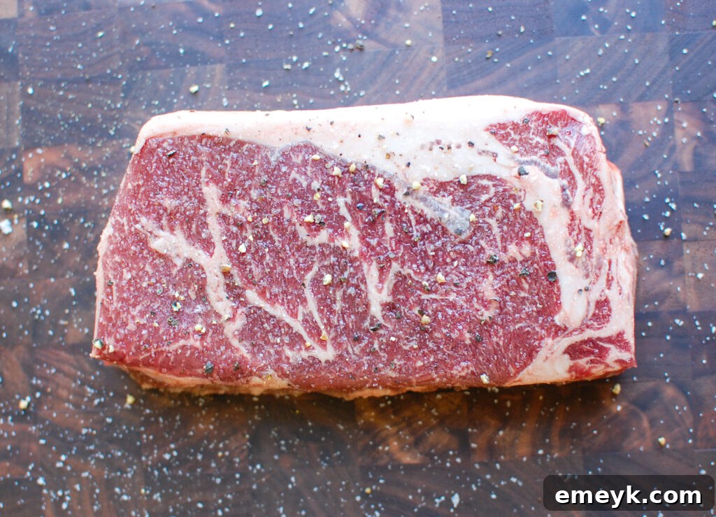 Perfectly grilled ribeye steak on a cutting board, garnished with fresh rosemary and sea salt flakes.