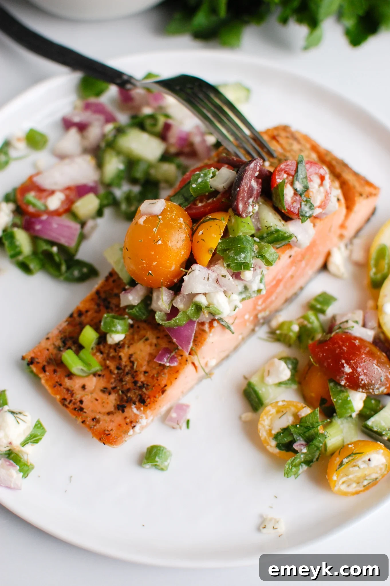Sundrenched Mediterranean Salmon Bake 5 A fork delicately flaking into a succulent piece of Mediterranean salmon, showcasing its tender, perfectly cooked texture.