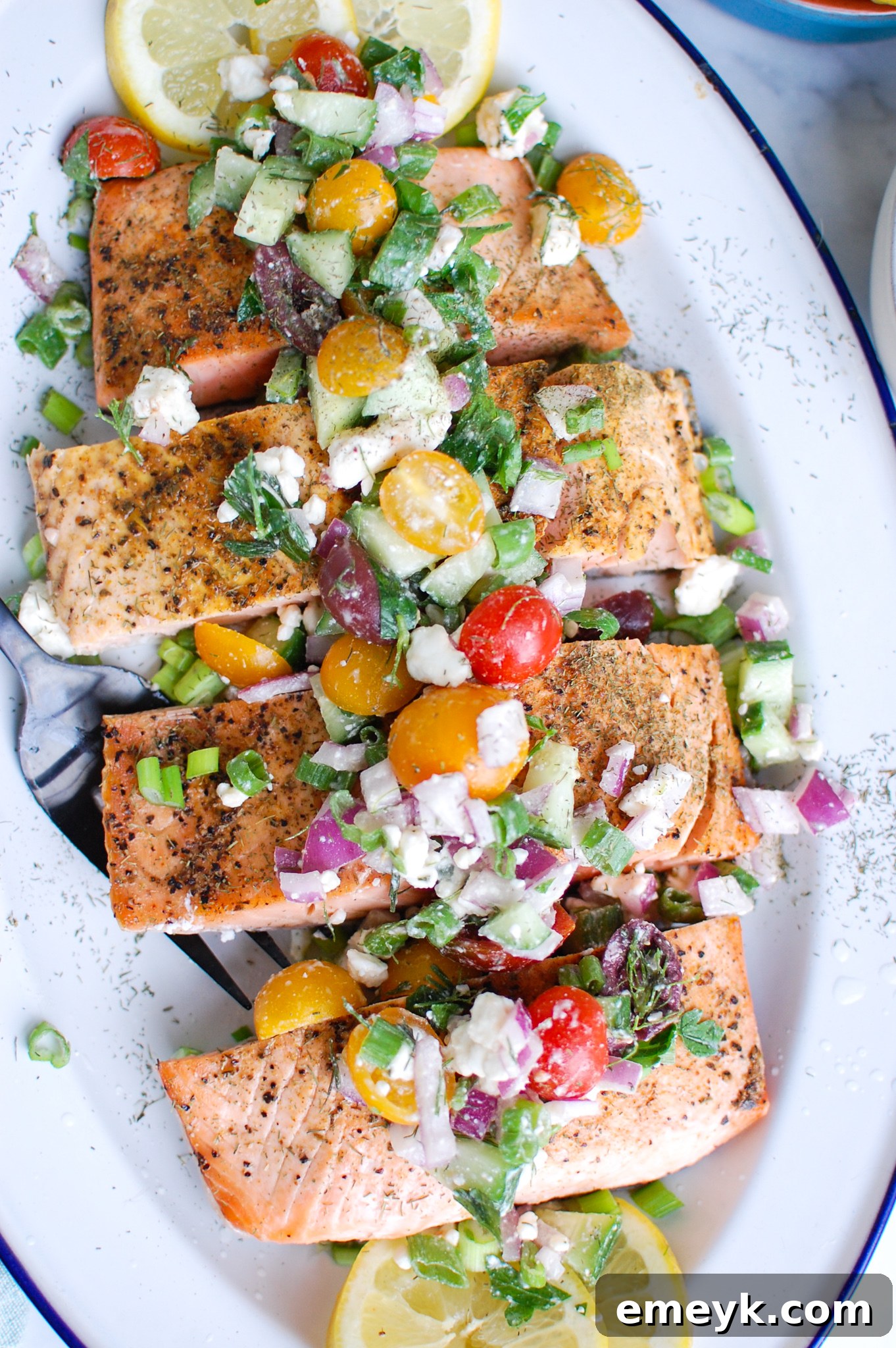 Sundrenched Mediterranean Salmon Bake 6 Beautifully arranged Mediterranean Salmon on a pristine white platter, garnished with fresh tomatoes, creamy feta cheese, and fragrant herbs, ready for serving.