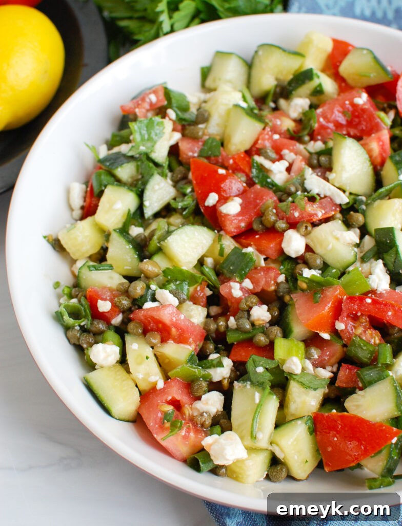 Vibrant Tomato and Cucumber Salad with Capers in a white bowl, ready to be served