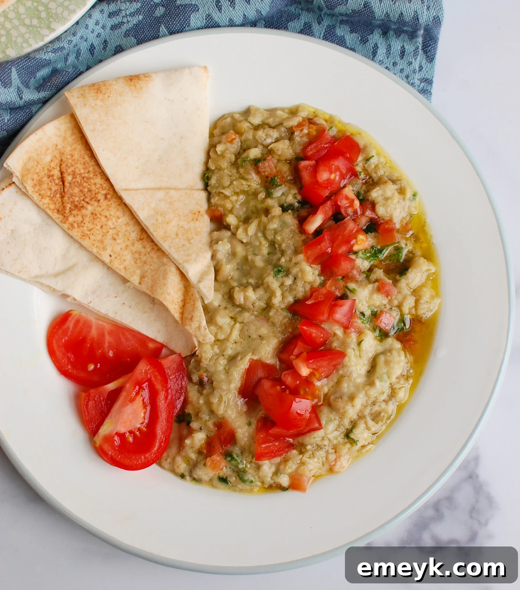 Close-up of Ful Medames generously topped with fresh diced tomatoes and parsley, emphasizing its appetizing appearance.