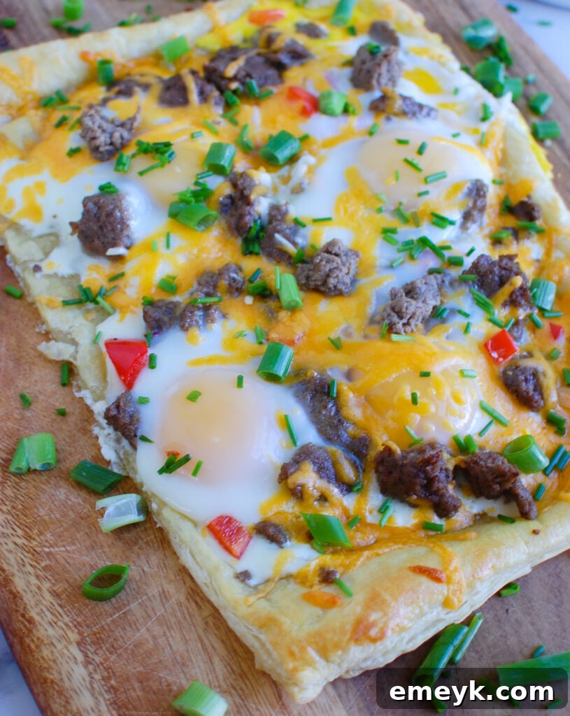 Golden brown Turkey Sausage and Egg Puff Pastry Pizza on a rustic wooden cutting board, garnished with fresh herbs and ready to serve.