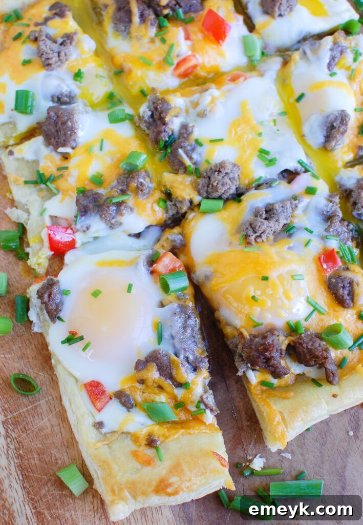 A large Turkey Sausage and Egg Puff Pastry Pizza, beautifully sliced into servings, ready for enjoyment.