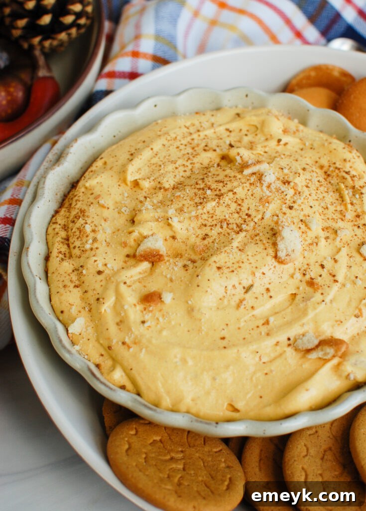 Close-up of creamy Pumpkin Dip in a bowl, surrounded by various dippers like cookies and apple slices