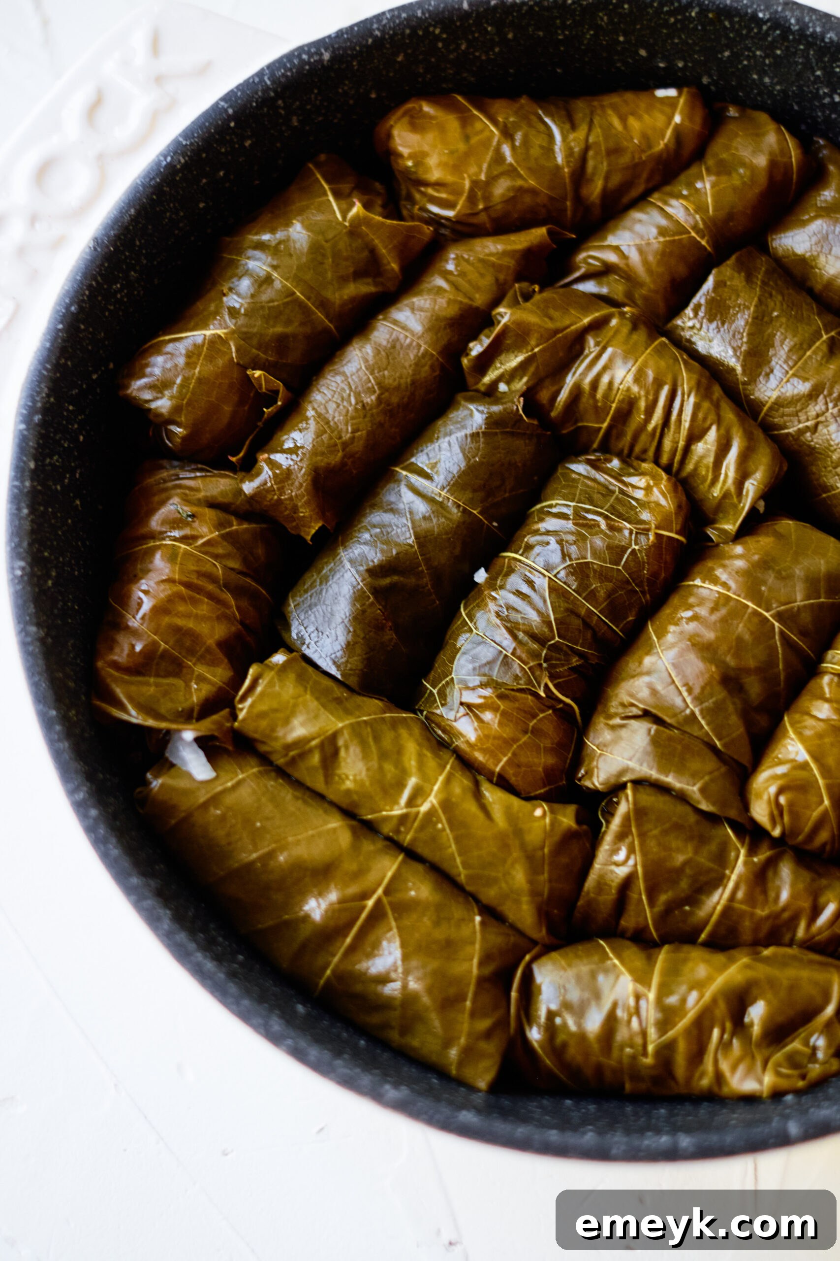 Effortless Homemade Dolma 6 Rolled stuffed grape leaves arranged in concentric circles in a large cooking pot, ready for simmering.
