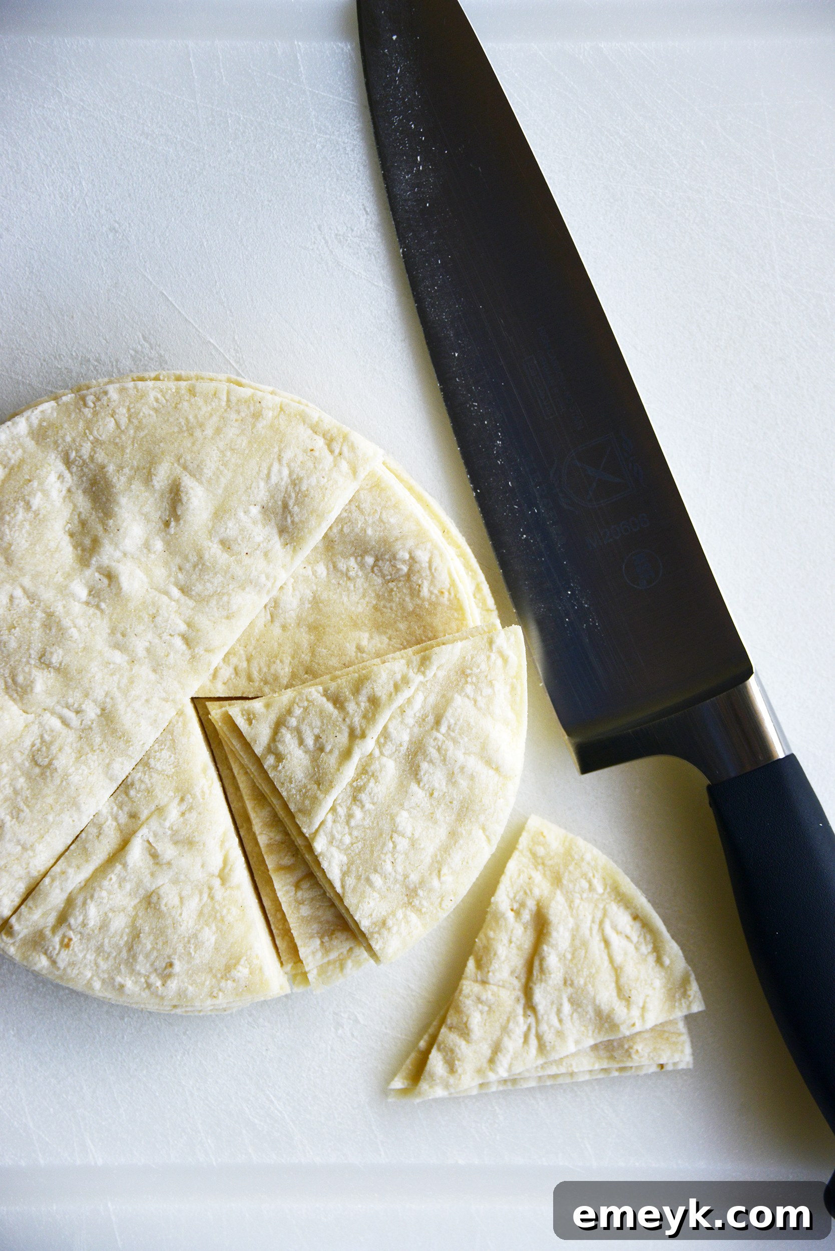Corn tortillas precisely cut into triangles, ready for seasoning and baking.